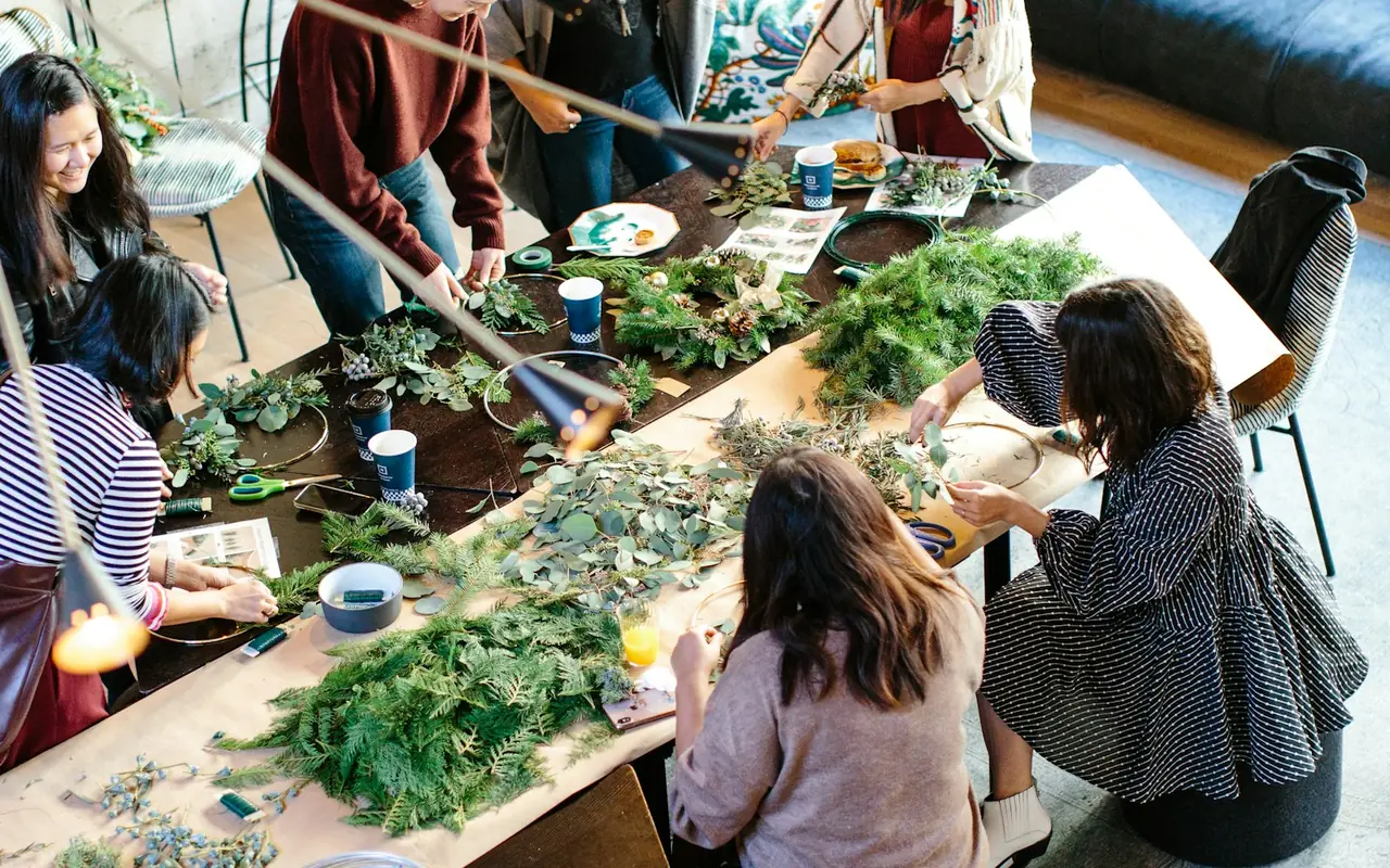 Two women arranging greenery at a workshop table.